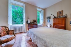 Chambre parentale avec vue sur le parc boisé, dans une maison de maître à Marseille, capturée par un photographe immobilier à