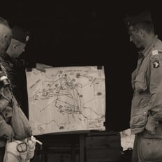 Trois soldats devant une carte du débarquement de 1944