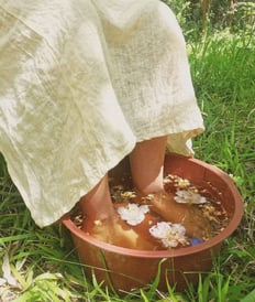 pies de mujer en recipiente con agua floral