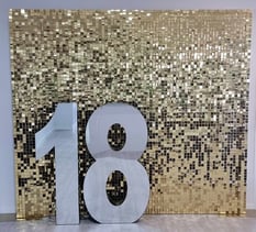 18 mirror infinity marquee number sitting in front of a gold shimmer wall in Brisbane before being turned on.