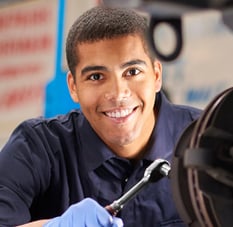 Homem usando jaleco azul e sorrindo para a camera enquanto trabalha