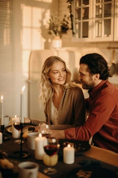 a man and woman sitting at a table with candles