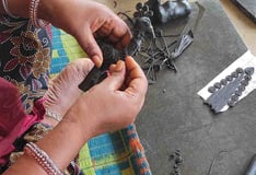 "Tribal artisan shaping wax mold to cast brass idol in traditional lost-wax method"