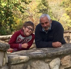 A photo of Ivan Poulter and his young son Nathaniel  leaning over a rock wall in a garden