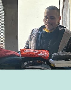Smiling man about to choose clothes from a donation area
