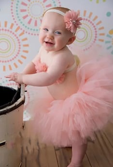 a happy, smiling baby girl in a pink tutu with a matching headband