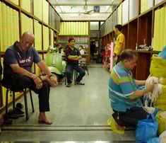 Men seated working in a textile shop in Chinatown, Bangkok, By ACAT Photos.