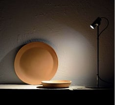 Foco de iluminación puntual destacando elementos decorativos sobre pared de textura natural