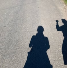 two people standing on a street with their hands up to their backs