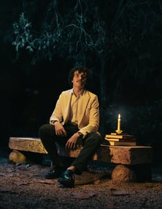 a man sitting on a bench with a candle lit up