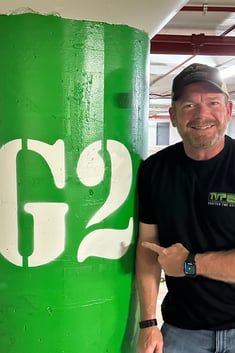 Andrew pointing at a sign in a parking garage that says G2