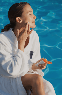 Girl applying SPF to her face as part of her Summer Skincare