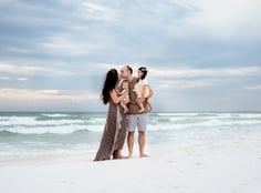 a family of four standing on a Florida white sand beach