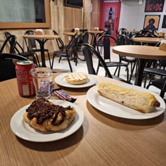 Lanches doces e salgados sobre mesa no lounge da cafeteria do Studio Brothers em Porto Alegre