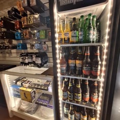 Geladeira com bebidas ao lado de acessórios musicais na loja do Studio Brothers em Porto Alegre