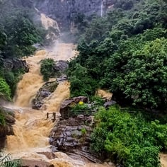 Rawana Waterfall near Ella, Sri Lanka, cascading down rocky cliffs surrounded by lush greenery on rainy day