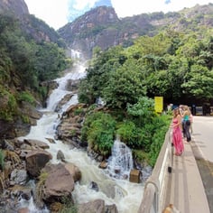 Rawana Waterfall near Ella, Sri Lanka, cascading down rocky cliffs surrounded by lush greenery and tourists nearby