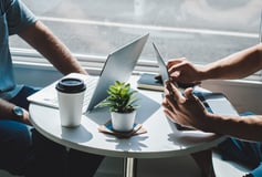 sustainability training, two persons sitting at a table with laptops, coffee and a little plant