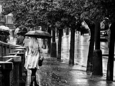 Photo d'une jeune femme femme blonde de dos qui marche sous la pluie a Pregue