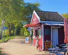 Der kleine Imbiss "Seeperle" am Plöner See mit Sonnenschein und Blick auf den Wanderweg