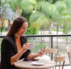 uma mulher sentada a uma mesa com uma xícara de café