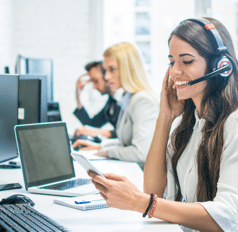 A happy customer service representative helps a customer over the phone.