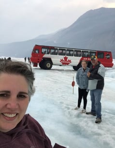 trish wozniak standing on an icefiel with her husband and daughter in the background