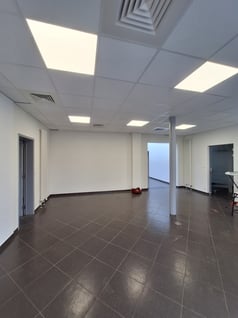 Une photo avant transformation de l'ancien showroom avec des murs blanc et un sol gris 