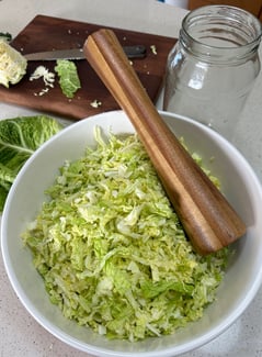 cabbage in a bowl with a wooden tamper