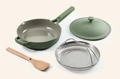 a set of three pots and pans with a wooden spoon