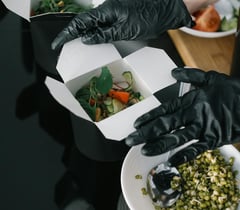 Bientôt disponible  Une personne portant des gants tenant une boîte de nourriture