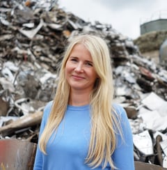 a woman in a blue shirt standing in front of a pile of rubble