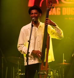 a man in a white shirt and hat playing bass