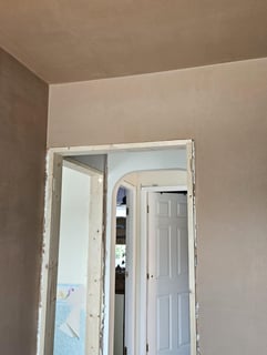 AN EMPTY ROOM THAT HAS BEEN PLASTERED AND A DOORWAY