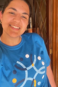 a woman in a blue shirt is smiling and holding a cake