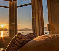 The bed at Gourock Seaview Holiday Let with a view of the sun setting over the water