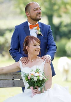 photo de couple pendant un mariage. la mariée est assise avec son bouquet comportant du orange