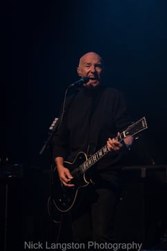 Midge Ure - singing with guitar and dark background - live at Chepstow Castle - music in Wales - Nick Langston