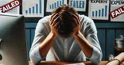 a person sitting on a desk looking overwhelmed with their head on their hands