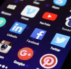 Display of popular social media app icons on a phone, representing social media management and digit