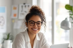 Emprendedora joven sonriente trabajando en laptop, representa productividad y liderazgo femenino en negocio digital en casa.