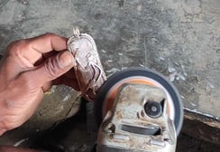 "A tribal artisan carefully filing and refining excess brass from a sculpture after casting in the traditional Dhokra art"