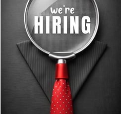 a we're hiring magnifying glass in front a black suit