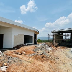 "A construction site featuring two distinct structures. The left structure is a circular building with scaffolding, while the