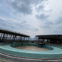 "A construction site featuring two distinct structures. The left structure is a circular building with scaffolding, while the