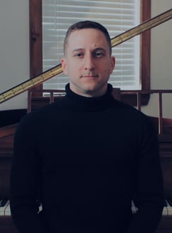 Photograph of Canadian composer Travis Reichstein in front of a piano