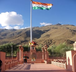 a flag flying in the wind at the base of a mountain