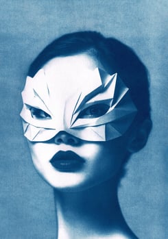 Portrait of a woman with bold lipstick, wearing a geometric paper mask resembling abstract feathers,