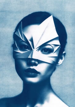 Close-up of a woman with dark hair, wearing an angular paper mask resembling a bird or superhero, ag