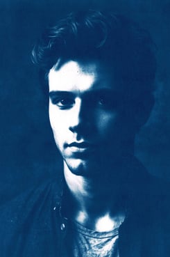 Close-up portrait of a young man with a strong jawline and high cheekbones, featuring dramatic light